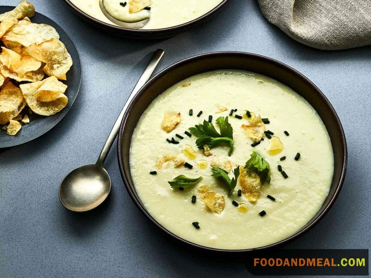 Spiced leek and potato soup in a ceramic bowl with a sprinkle of dill and a side of crusty bread